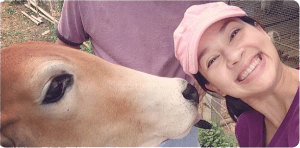 แหม่ม คัทลียา smiles next to a cow on Sirin Farm in Chiang Rai Thailand